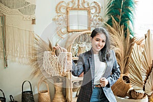 a businesswoman in a blazer carries a woven bag as she stands against a multicraft background photo