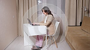 Businesswoman in blouse under jacket and pyjama at laptop
