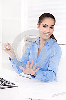 Businesswoman in a blue blouse is making her nails at desk and g