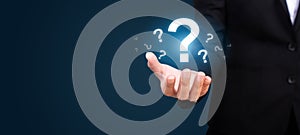Businesswoman on blurred background holding hand question marks