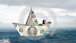 Businesswoman in boat made of dollar banknote