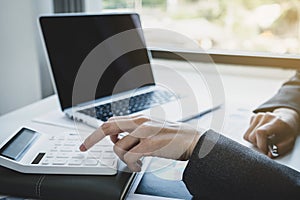 Businesswoman bookkeeper hand use calculator and analysis the graph with laptop at the home office for setting challenging