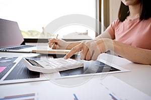 Businesswoman bookkeeper hand use calculator and analysis the graph with laptop at the home office for setting challenging