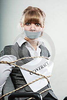 Businesswoman bound by contract with taped mouth.