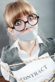 Businesswoman bound by contract with taped mouth.