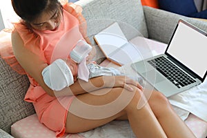 Businesswoman breastfeeding milk her baby and working with laptop computer