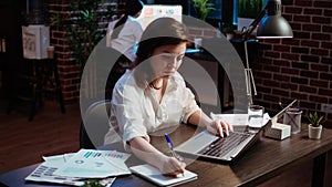 Businesswoman in brick wall office focused on finishing company project