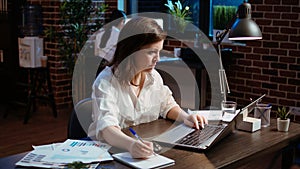 Businesswoman in brick wall office focused on finishing company project