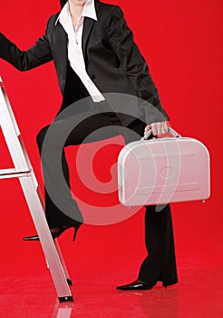 Businesswoman with briefcase walking up the ladder