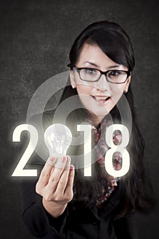 Businesswoman with bright bulb and numbers 2018