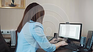 Businesswoman brunette sitting in the office and typing on the computer keyboard.