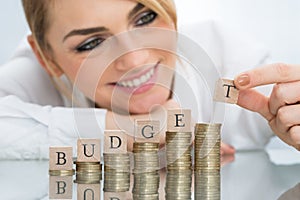 Businesswoman with budget blocks on stacked coins