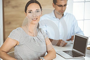 Businesswoman and businessman discussing questions while using a computer in modern office. Portrait of female latin