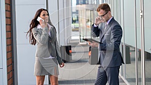 Businesswoman and businessman working outside with mobile phone and tablet pc.