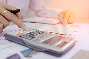 Businesswoman calculate about cost and charts report on table, calculator on desk of financial planing. Finance concepts.