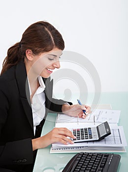 Businesswoman Calculating Bills At Desk