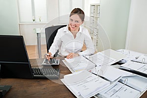 Businesswoman Calculating Financial Data At Desk