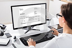 Businesswoman Calculating Invoice On Computer