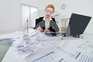 Businesswoman Calculating Invoice At Desk