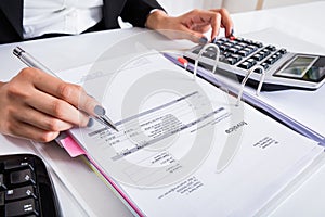 Businesswoman Calculating Invoice Using Calculator