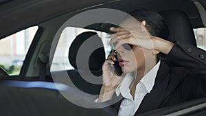 Businesswoman in car talking over mobile phone gesturing angrily, failed deal