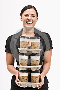 Businesswoman carrying stack of coffee cups