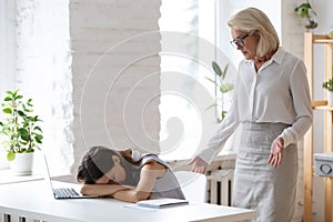 Businesswoman catch female employee sleeping at workplace