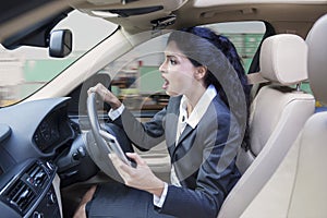 Businesswoman with cellphone driving car