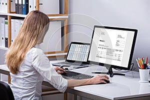 Businesswoman Checking Invoice On Computer