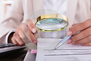 Businesswoman Checking Invoice With Magnifying Glass