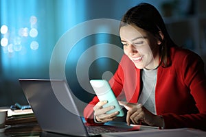 Businesswoman checking phone smiling at home