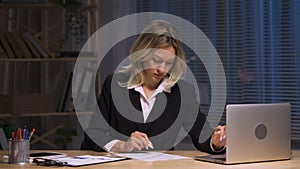 Businesswoman checking and signing by pen contract. Woman in business suit sits at table in office. Signing on working