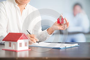 Businesswoman choosing mini house model from model on wood table