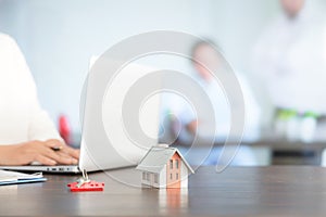 Businesswoman choosing mini house model from model on wood table