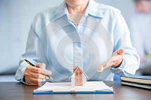 Businesswoman choosing mini house model from model on wood table