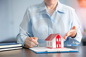 Businesswoman choosing mini house model from model on wood table