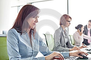 Businesswoman with colleagues working in open plan office