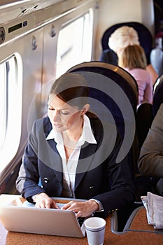 Businesswoman Commuting To Work On Train And Using Laptop
