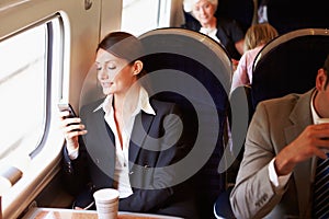 Businesswoman Commuting To Work On Train Using Mobile Phone