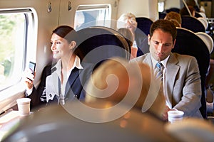 Businesswoman Commuting To Work On Train Using Mobile Phone