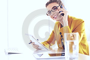 Businesswoman concentrating on work, using computer and cellphone in office