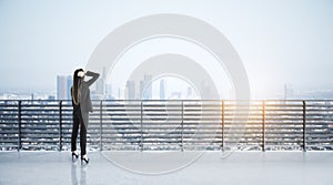 Businesswoman on concrete balcony looking into the distance at city with mock up place.