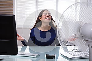 Businesswoman Cooling Herself With Electric Fan