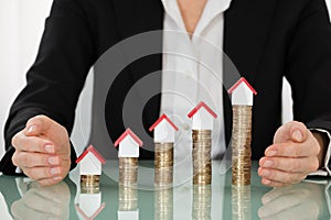 Businesswoman Covering House Models On Stacked Coins