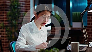 Businesswoman crosschecking data between financial charts and laptop