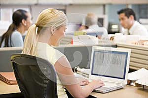 Businesswoman in cubicle using laptop