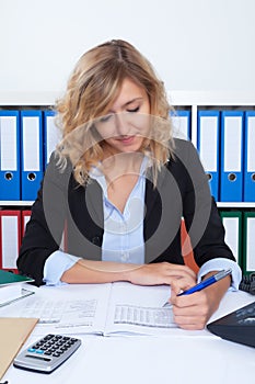 Businesswoman with curly blond hair writing note