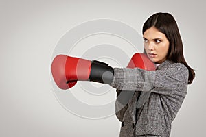 Businesswoman in defensive stance with boxing gloves