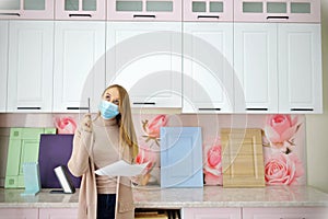 Businesswoman designer girl in mask approves the cabinet furniture project remotely. The planning of the kitchen. The concept of