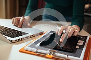 Businesswoman or Designer using tablet with laptop and document on desk in modern office.